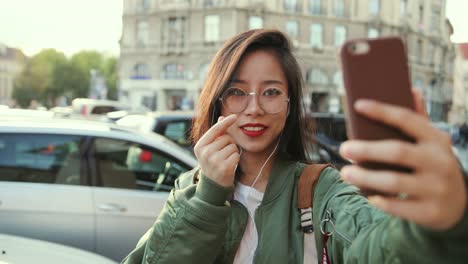 Close-Up-Of-The-Happy-Beautiful-Young-Woman-In-Glasses-Posing-To-The-Camera-Of-Smartphone-While-Taking-Selfie-Photos