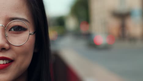 Close-Up-Of-The-Half-Face-Of-The-Young-Pretty-Woman-In-Glasses-Smiling-Cheerfully-And-Looking-Straight-To-The-Camera-Outside