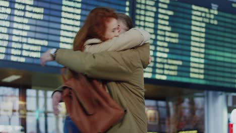 Young-Guy-With-A-Beard-Arriving-From-A-Trip-To-The-Airport-And-Walking-Through-The-Arrival-Hall,-Then-Young-Pretty-Girlfriend-Meeting-Him-And-Hugging-Tight
