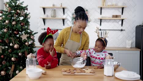 Happy-Mom-With-Little-Cute-Kids-Standing-At-Table-In-Home-Kitchen-On-Christmas-And-Making-Ornate-Xmas-Cookies