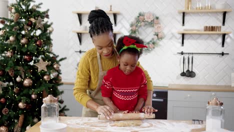 Portrait-Of-Mother-With-Little-Cute-Kid-Standing-At-Table-In-Home-Christmassy-Decorated-Kitchen-And-Making-Dough-For-Xmas-Cookies-Mom-Teaching-Small-Daughter-To-Bake-Biscuits-New-Year