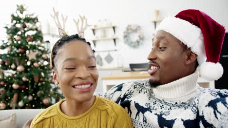 POV-Eines-Glücklichen-Paares-Von-Mann-Und-Frau-Zu-Hause-Mit-Geschmücktem-Weihnachtsbaum-Online-Video-Chats-Und-Urlaubsgrüße-An-Freunde-Und-Verwandte