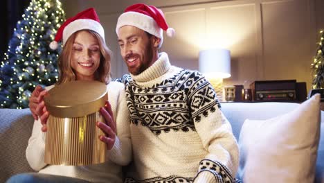 Close-Up-Portrait-Of-Joyful-Wife-Receiving-And-Opening-Christmas-Gift-Box-From-Husband-At-Home