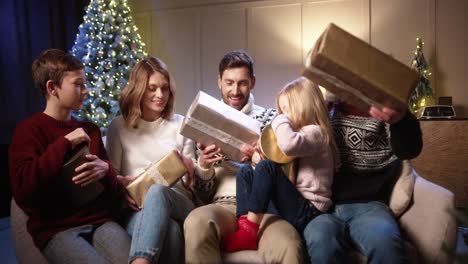 Glückliche-Familie-Versammelte-Sich-In-Einem-Gemütlichen-Haus-In-Der-Nähe-Eines-Geschmückten-Glühenden-Weihnachtsbaums,-Der-Lächelte-Und-Sich-Am-Heiligabend-Am-Abend-Weihnachtsgeschenke-Gab