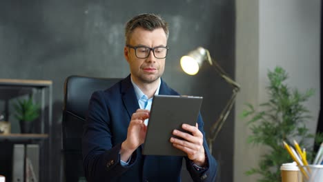 Hombre-De-Negocios-Con-Gafas-Usando-Tableta-En-La-Oficina
