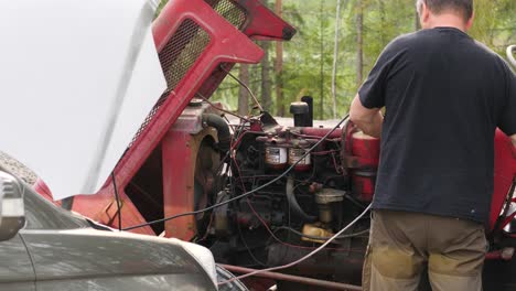 Static-shot-of-a-mechanic-repairing-an-old-tractor-motor,-on-a-sunny,-summer-day,-in-Ostrobothnia,-Finland