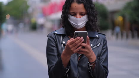 Woman-on-phone-checking-latest-government-updates-wearing-mask-in-city-during-covid19-outbreak-and-lockdown