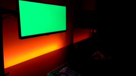 Green-screen:-Caucasian-hands-on-dark-keyboard-with-display-monitor-above-yellow-and-orange-lights
