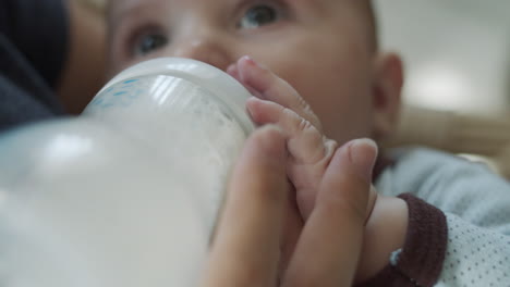 Close-up-on-baby's-hands-holding-a-bottle-with-baby-nutrition-during-feeding