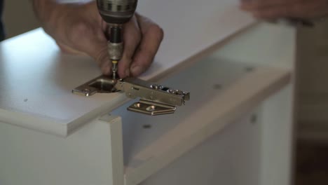 Hand-using-power-tools-l-to-secure-hinges