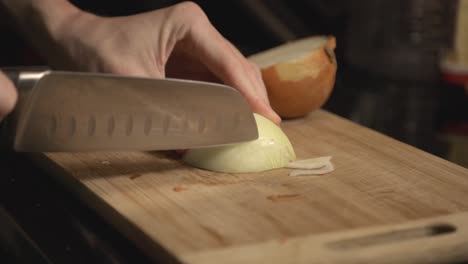 Chopping-A-White-Onion-Into-The-Wooden-Chopping-Board-For-Cooking