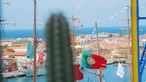 Barco-Alto-Con-Muchas-Banderas-Ondeando-En-El-Viento-Con-Los-Colores-Nacionales-De-México,-Perú-Y-Portugal-Mientras-Está-Amarrado-En-Curaçao