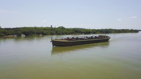 Shipping-on-the-Jacui-River-as-barge-travels-down-stream,-aerial-pan-shot