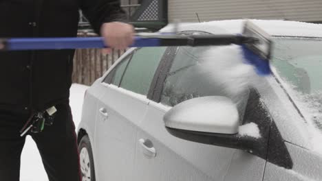 A-Man-Scraping-Layers-Of-Ice-Build-Up-On-The-Roof-Of-His-Car---Medium-Shot