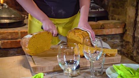Chef-woman-cuts-black-bread-into-slices-Podvelka,-Slovenia,-slowmo-dolly