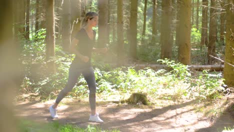 A-pretty-blonde-woman-wearing-athletic-apparel-starts-to-run-down-a-forest-path