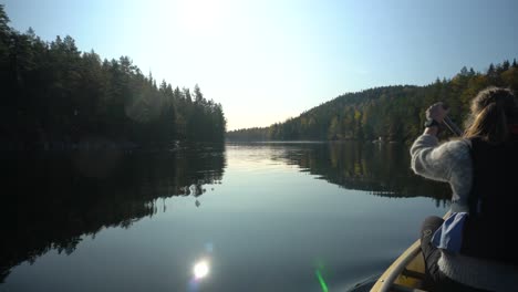 Woman-paddling-canoe-boat-on-beautiful-autumn-lake,-rear-view