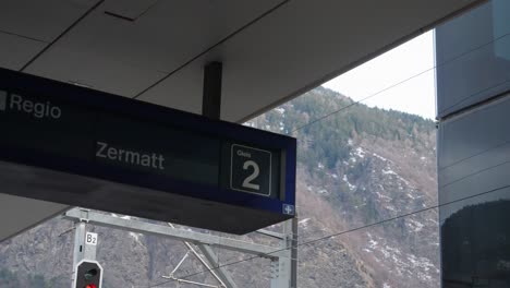 Plano-Fijo-De-La-Estación-De-Tren,-Tren-Saliendo-Hacia-Zermatt,-Nombre-Colocado-Bajo-El-Techo