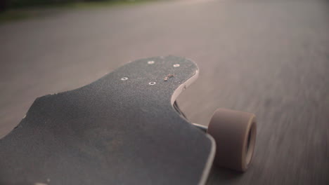 Low-angle-perspective-of-longboard-as-it-rides-down-the-road-at-golden-hour