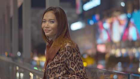 Wunderschöne-Asiatische-Frau-Lächelt-Und-Flirtet-Mit-Der-Kamera-Unter-Den-Hellen-Nachtlichtern-Der-Stadt