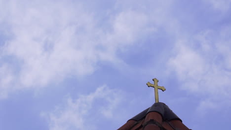 Techo-De-La-Iglesia-Católica-Cruz-Dorada-Con-Nubes-Rápidas-Y-Cielo-Azul