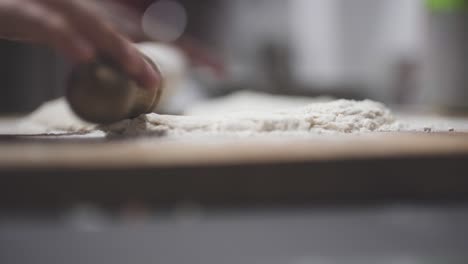 Man-making-a-pizza-dough-with-the-rolling-pin-in-the-kitchen