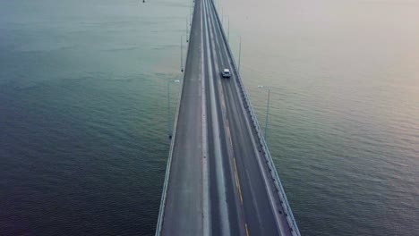 Aerial-reveal-of-a-large-bridge-over-ocean-at-sunrise