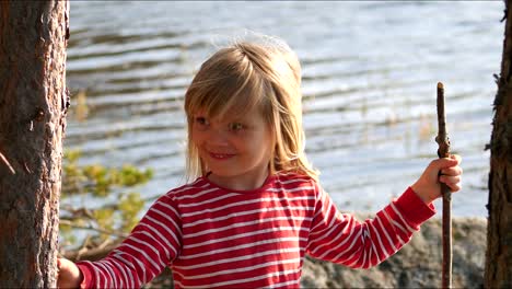 Portrait-shot-of-happy-cute-girl-holding-a-stick-by-the-water,-slow-motion