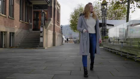 Confident-young-blonde-woman-taking-a-stroll-down-an-empty-city-street