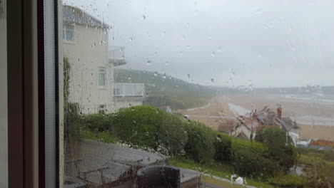 Rain-Drops-Hitting-a-Glass-Window-with-a-Beach-View-in-Slow-Motion
