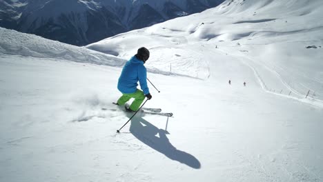 FOLLOW-TRACKING-SLOW-MOTION:-Young-skier-skiing-with-fast-turns-on-a-beautiful-winter-day-on-perfect-slope-at-ski-resort-in-the-swiss-Alps-during-cloudless-day