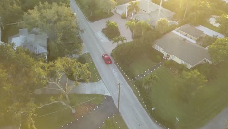 Luftaufnahme-Des-Roten-Sportwagens,-Der-Bei-Sonnenuntergang-Durch-Die-South-Florida-Street-Fährt-1