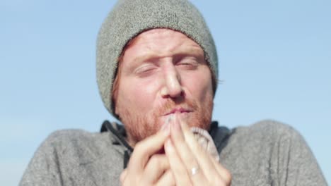 A-close-shot-of-the-face-of-a-ginger-haired-man-sneezing-into-a-handkerchief-and-wiping-his-nose