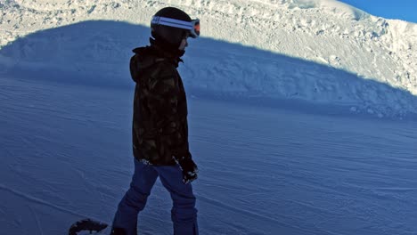 A-teenage-boy-on-a-snowboard-sliding-by-slowly