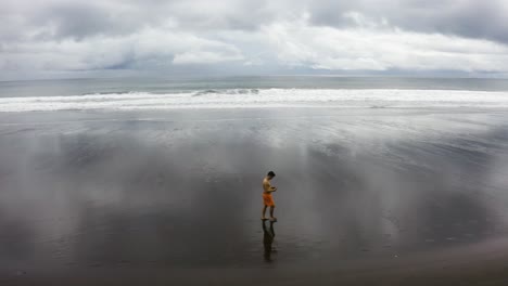 Aerial-shot-of-a-young-man-walking-on-an-empty-beach,-Colombia