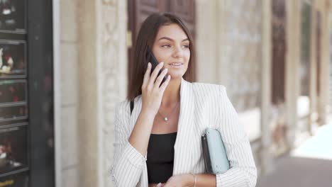 Beautiful-young-business-woman-walking-and-talking-on-a-smart-phone