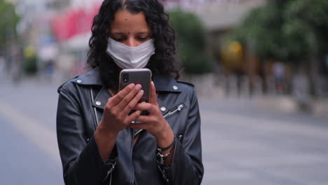 Woman-on-phone-checking-latest-government-updates-wearing-mask-in-city-during-covid19-outbreak-and-lockdown-1