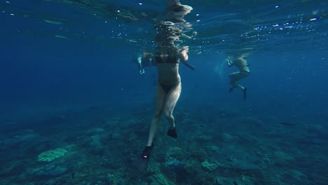 Unter-Wasser-Blick-Auf-Junge-Frauen,-Die-Im-Blauen-Ozean-Schnorcheln-Und-Luft-Schnappen