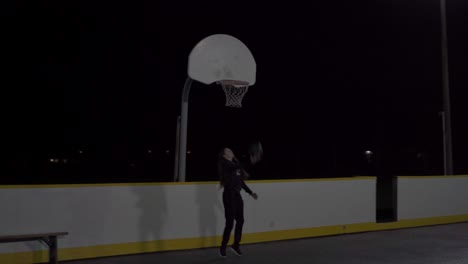 Girl-runs-and-does-a-layup-in-an-outdoor-basketball-court-at-night-with-lights