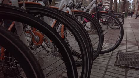 Row-of-Bicycles-Locked-Up-on-Sidewalk,-Close-Up-Detail-of-Bike-Tires
