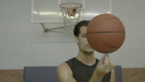 Mann-Dreht-Basketball-Am-Finger-Und-Schaut-In-Die-Kamera,-Nahaufnahme