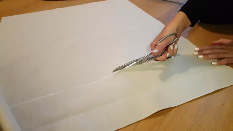 Woman-Tailor-Hands-Cutting-White-Fabric-Material-With-Scissors-in-Sewing-Studio