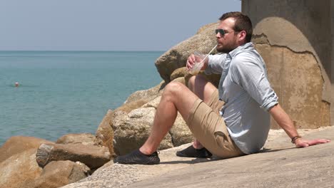 Man-sips-drinks-and-relaxes-contemplating-sea
