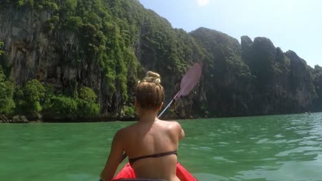 Close-Up-of-the-Back-of-a-Girl-Kayaking-on-the-Sea-Close-to-Beautiful-Mountains