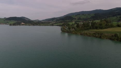 Vuelo-Sobre-El-Lago-En-Día-Nublado,-Lago-Gruyère,-Suiza