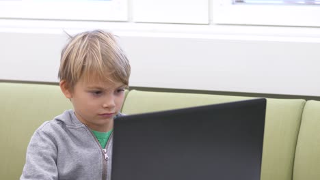 Nordic-school-boy-reading-from-laptop-screen,-Static-medium-shot