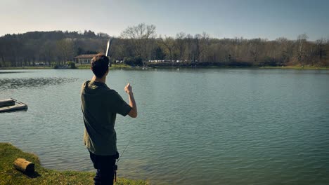 Young-man-using-a-small-curved-tube-to-throw-bait-into-the-water