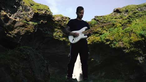 Hombre-Tocando-La-Guitarra-Frente-A-Una-Hermosa-Cascada-En-Islandia