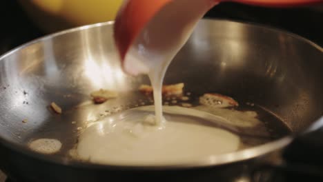 Pouring-While-Swirling-Ladleful-Batter-To-The-Frying-Pan-Making-An-Even-Layer-Of-Pancake---Close-Up-Shot