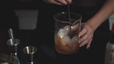 Close-up-of-bartender-mixing-craft-cocktail-in-ice-with-tall-bar-spoon
